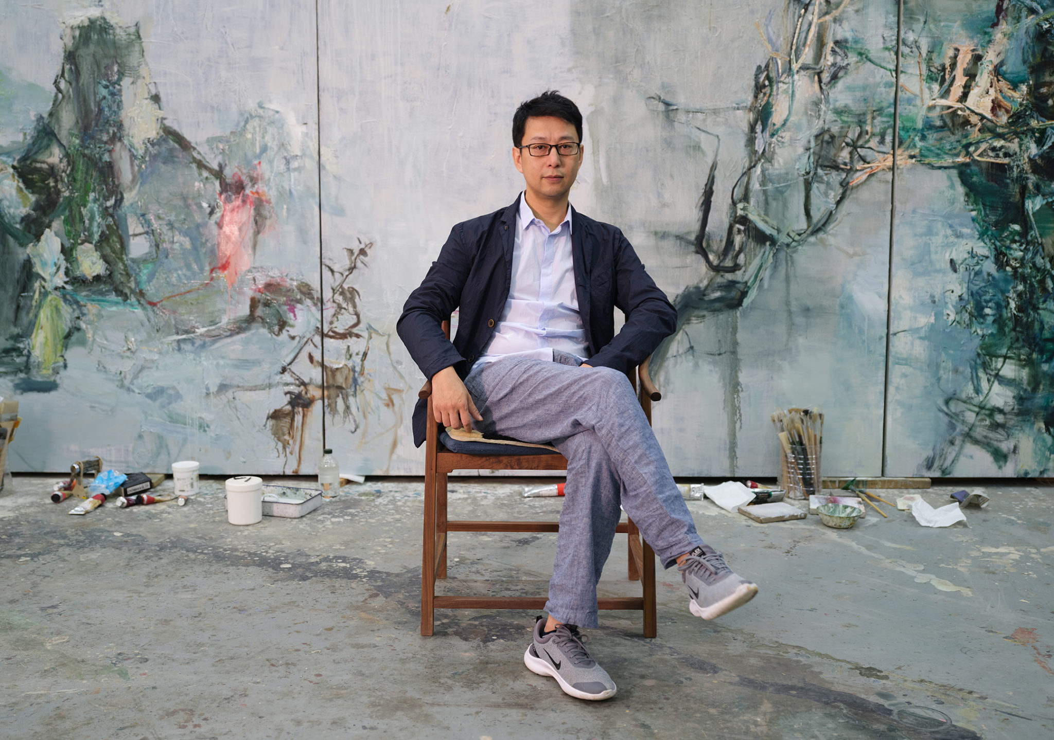 Portrait of artist Tu Hongtao sitting in front of his painting